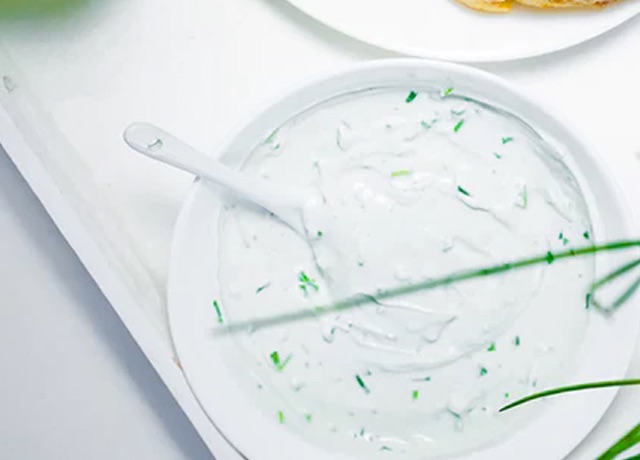 A white cream soup with vegetable, a spoon is put on the bowl.