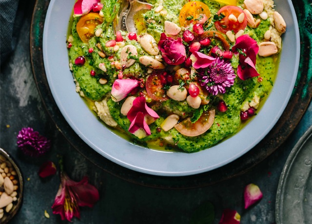 A vegetable soup with tomato, peanut, broccoli and pomegranate.