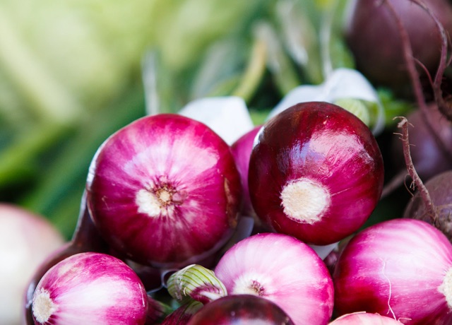 Some purple turnips with green leaves.
