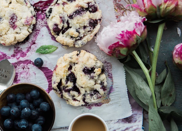 Some blueberry coockies on napkin, decorated by pink fresh flowers.